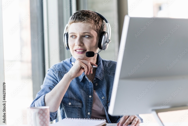 Businesswoman wearing headset at desk in office